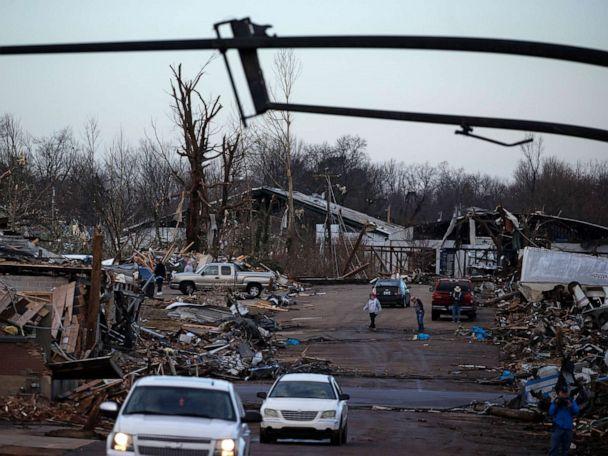 Martin Bolton (L) and shop owner Danny Wagner try to shut off a leaking gas meter after his automobile repair shop was destroyed by a tornado in Mayfield, Kentucky, on December 11, 2021 (AFP/John Amis)